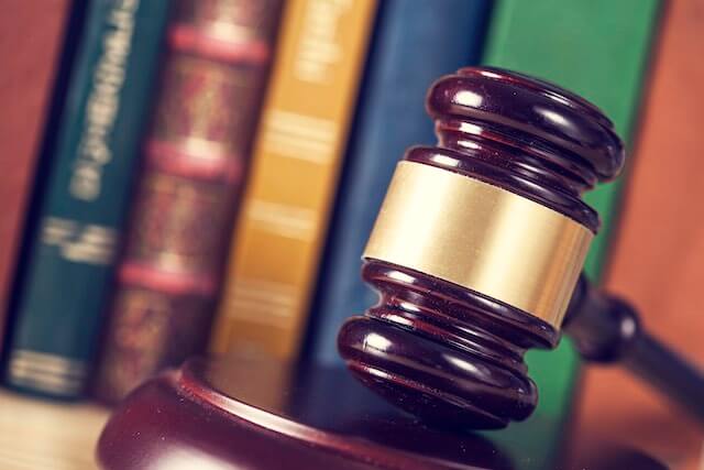 Wooden judge's gavel with law books pictured in the background