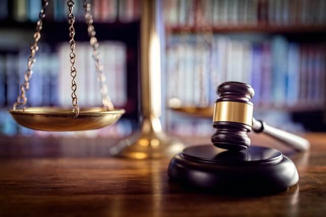 Wooden judge's gavel on a desk next to a justice scale