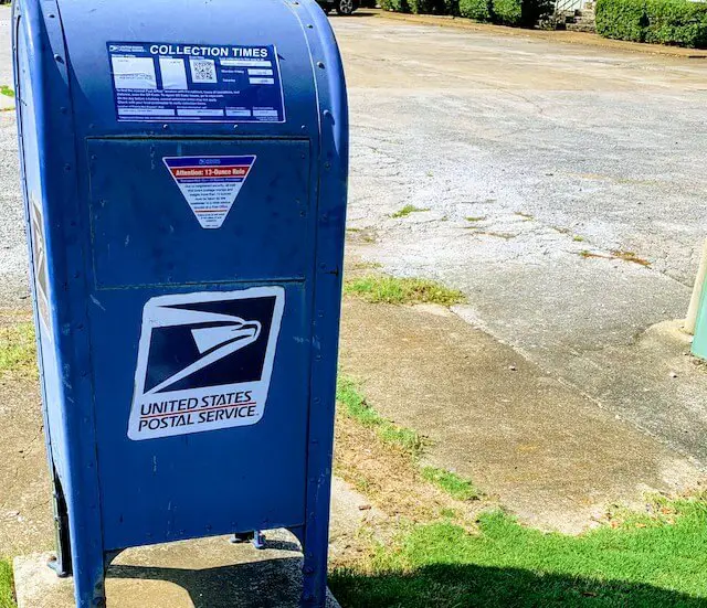 Postal Service (USPS) blue mailbox pictured on a street corner
