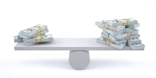 Two stacks of cash on the ends of an evenly balanced balance beam; the stack on the left is smaller than the one on the right