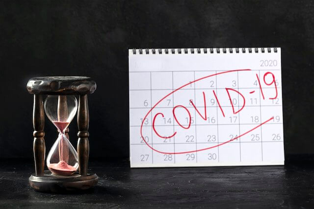 Hourglass next to a calendar with 'COVID-19' written across it