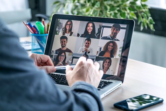 Back view of male employee speaking on video call with diverse colleagues on online briefing with laptop at home