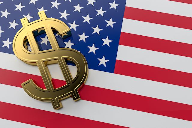 Three-dimensional golden dollar sign on top of an american flag