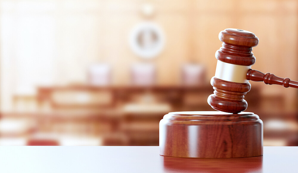 Wooden judge's gavel with a blurred image of a courtroom pictured in the background