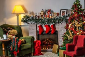 Christmas decorations in a home - stockings hung over the fireplace, a Christmas tree, and candles on the hearth