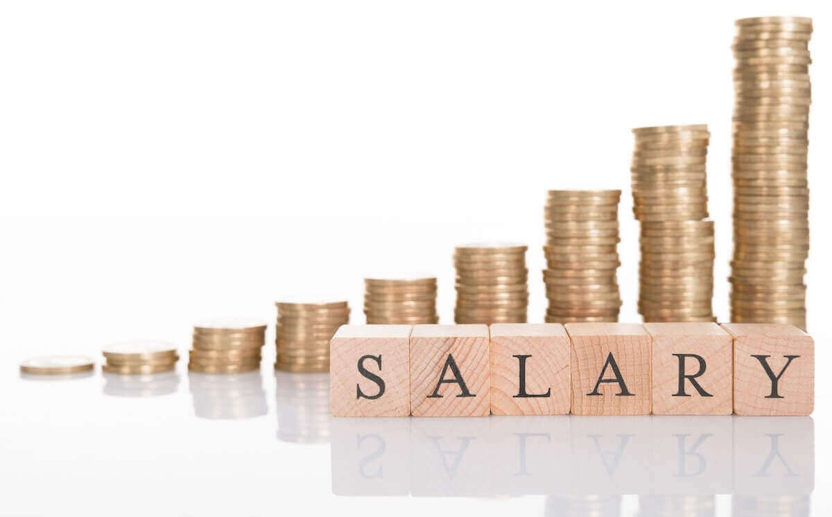 Vertical stacks of coins getting taller in size going from left to right against a solid white background with the word 'salary' written out in blocks in front of the coins