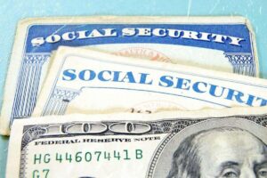 Close up of two social security cards with a $100 bill on top of them