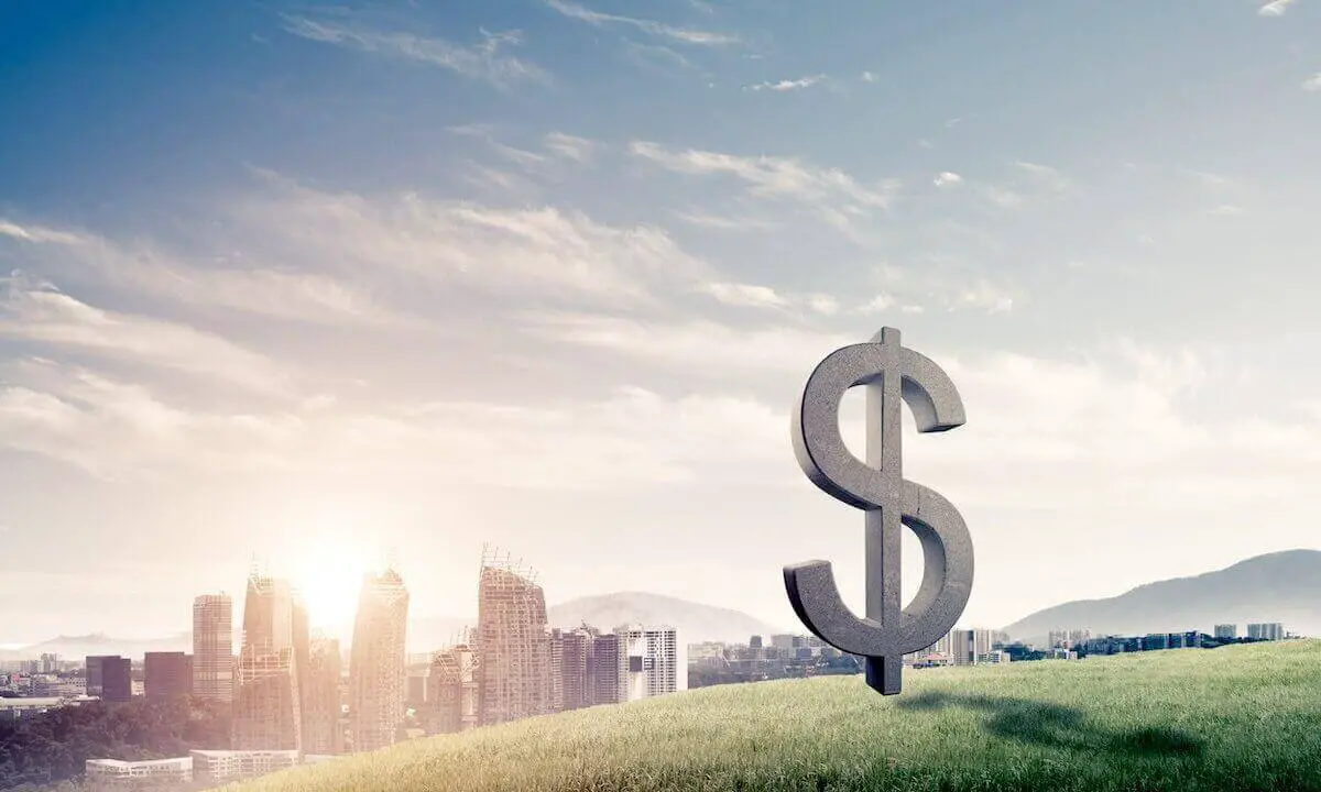 3D dollar sign pictured on green grass on a hill overlooking a city skyline with the sun setting in the background