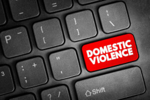 Close up of a red key with words 'domestic violence' in white letters on a computer keyboard