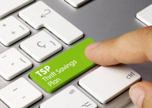 Close up of a person's finger touching a green key on a keyboard with white letters that read 'TSP Thrift Savings Plan'