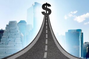 Dollar sign at the end of a road overlaid against a city skyline