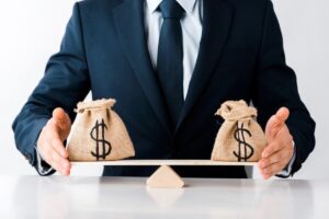 Businessman using his hands to balance a scale with a bag of money on each side