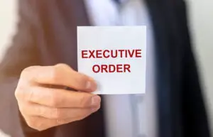 Close up of a businessman's hand holding a white notecard that reads 'executive order'