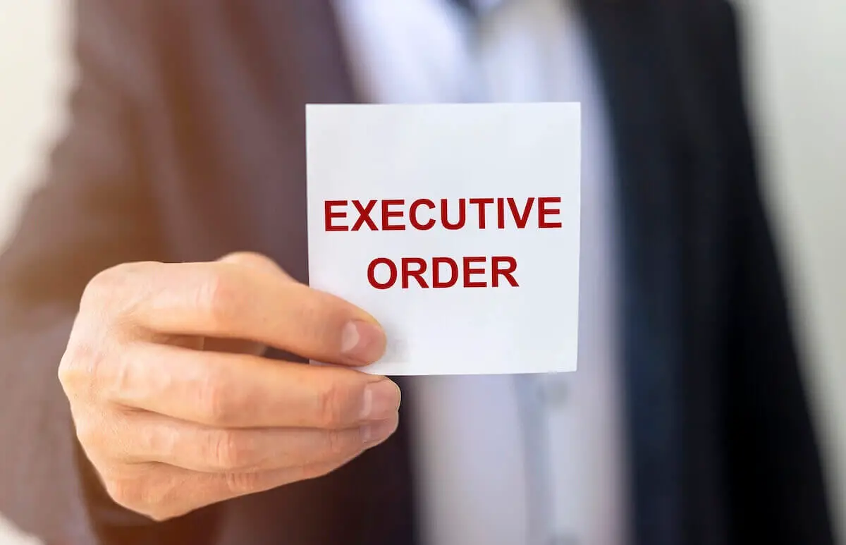 Close up of a businessman's hand holding a white notecard that reads 'executive order'