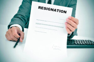 Close up of a businessman presenting a pen and a letter with the word 'resignation' at the top