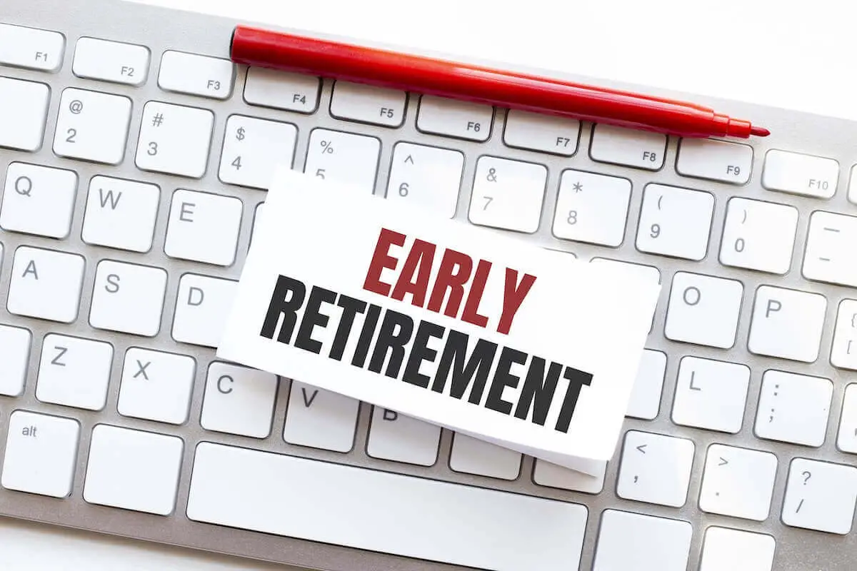 Notecard with the words 'early retirement' on a keyboard; a red pen is lying at the top of the keyboard
