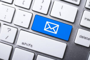 Close up of a blue button on a computer keyboard with a white email icon on it