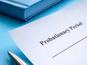 Sheet of paper on a desk titled 'probationary period' with a pen next to it