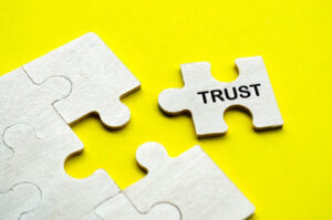 Puzzle piece with the word 'trust' on it against a yellow background