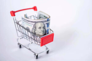 Small wad of $100 bills in a shopping cart against a white background