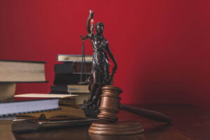 Wooden judge's gavel on a desk next to books and justice scales