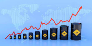 Barrels of oil growing in size from left to right with a red trendline arrow above them heading in a rising direction