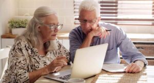 Retired couple sitting at a desk and looking at a computer in a planning meeting