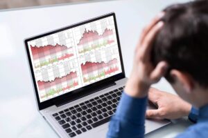 View of a worried businessman from behind as he looks at charts showing financial losses on a computer screen